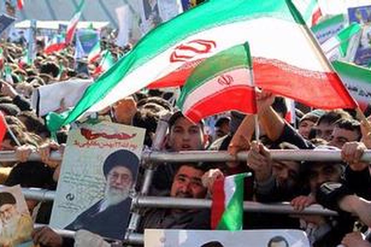 Rakyat Iran membawa foto-foto pemimpin tertinggi Ayatollah Ali Khamenei sambil melambaikan bendera nasional dalam perayaan 33 tahun Revolusi Islam Iran di Lapangan Azadi di Teheran, Sabtu (11/2/2012). 