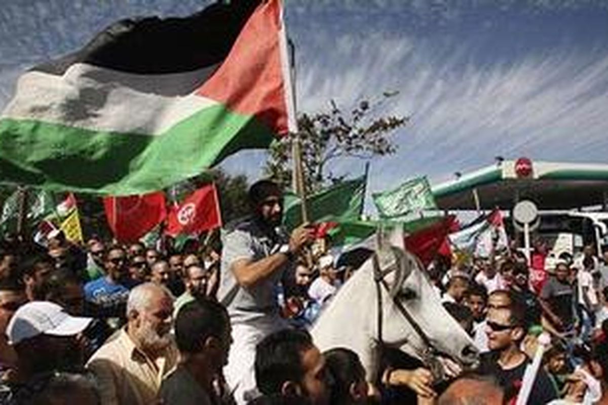 Seorang bekas tahanan Palestina yang dibebaskan Israel menunggang kuda dan membawa bendera Palestina dalam acara penyambutan di Gaza.   