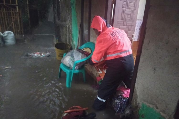 Seorang petugas BPBD Kota Bogor sedang membantu mengevakuasi barang-barang dari salah satu rumah warga yang terdampak banjir di Kelurahan Cikaret, Kecamatan Bogor Selatan, Kota Bogor, Selasa (8/10/2019).