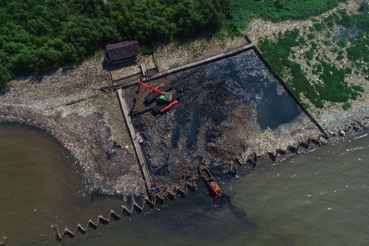 Petugas membersihkan lautan sampah yang menumpuk di kawasan Teluk Jakarta, Muara Angke, Jakarta Utara, Minggu (18/3/2018). Pencemaran limbah domestik rumah tangga di Teluk Jakarta ini memenuhi perairan seluas 7.500 meter persegi.