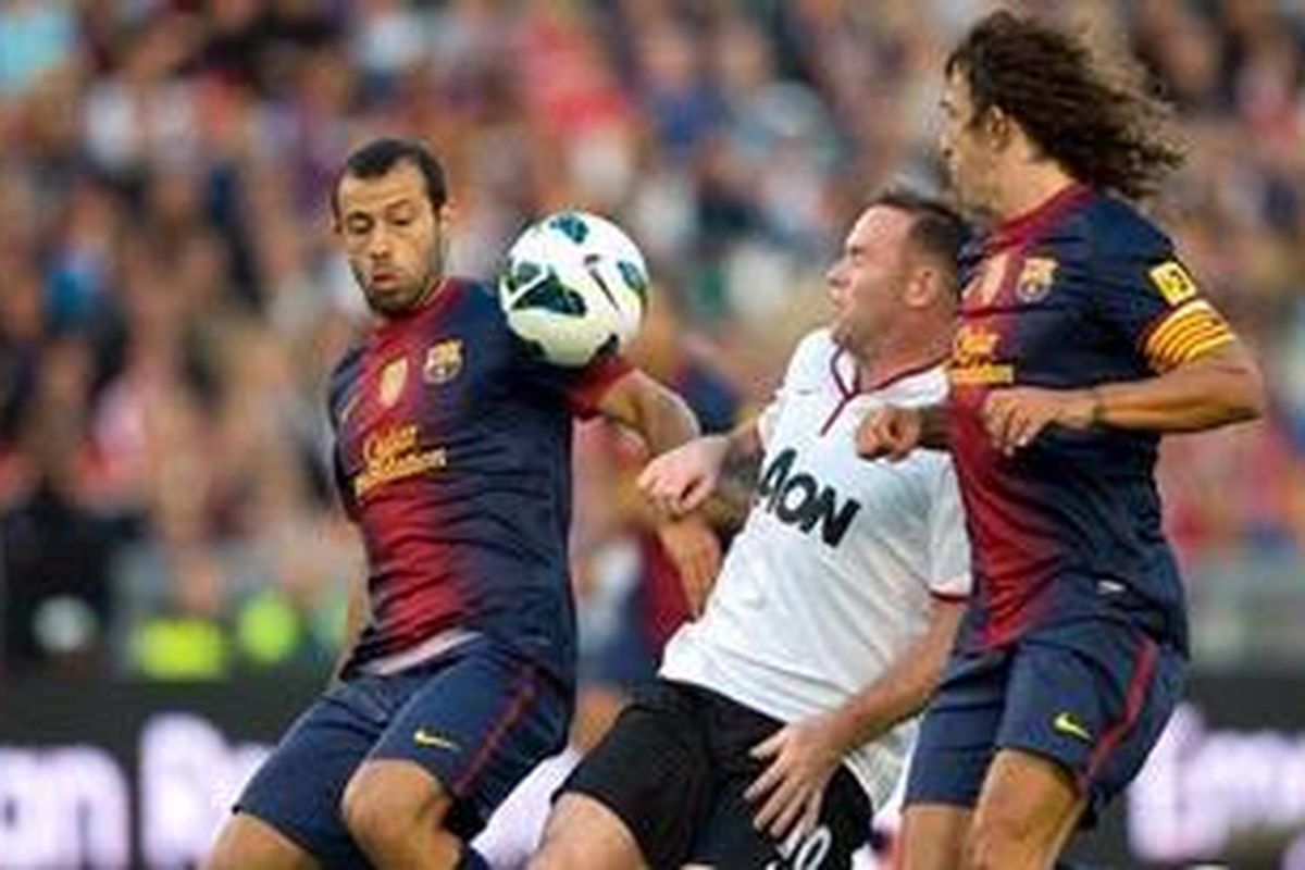 Bomber Manchester United, Wayne Rooney (tengah), bertarung dengan dua bek Barcelona, Javier Mascherano (kiri) dan Carles Puyol, dalam laga uji coba di Stadion Ullevi, Gothenburg, Rabu (8/8/2012). 