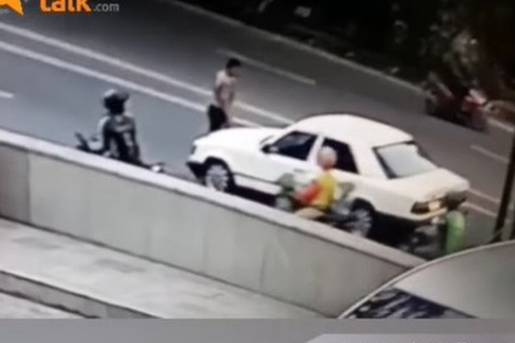 Tangkapan layar video viral memperlihatkan seorang sekuriti sebelum ditabrak sedan berwarna putih usai memberi akses jalan mobil lain di Jalan Pattimura, Medan.