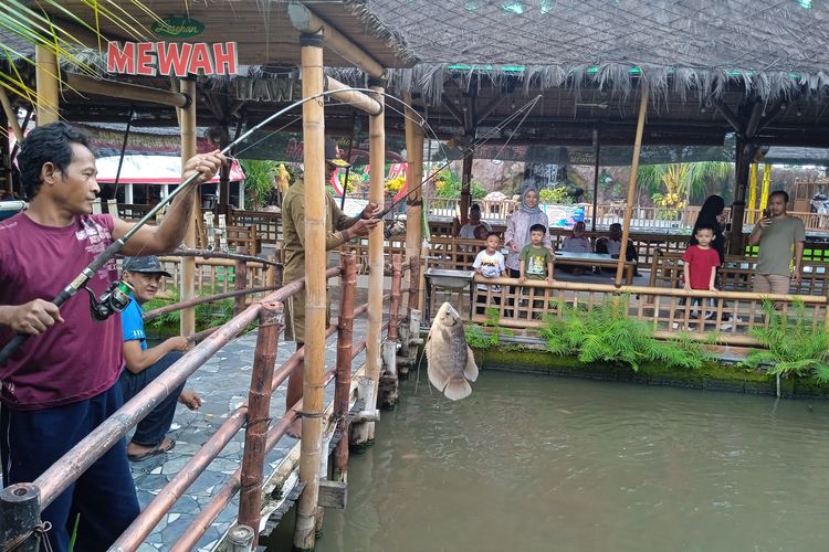 Salah satu pengunjung berhasil memancing ikan gurame di Lesehan Mewah Nganjuk untuk kemudian diolah, Senin (13/1/2025).