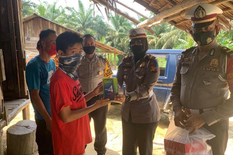 Kharisma Waruwu, siswa kelas VII SMP Negeri 2 Minas menerima sebuah handphone bantuan untuk belajar dari Kapolres Siak di rumahnya Jalan Banjar 11, Dusun Sarindo, Kampung Mandiangin, Kecamatan Minas, Kabupaten Siak, Riau, Minggu (2/8/2020). Dok Polres Siak.