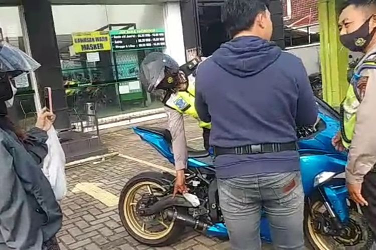 Anggota kepolisian menunjuk knalpot racing sepeda motor yang disebut ditilang saat baru beli dari diler, Kamis (23/6/2022) siang.