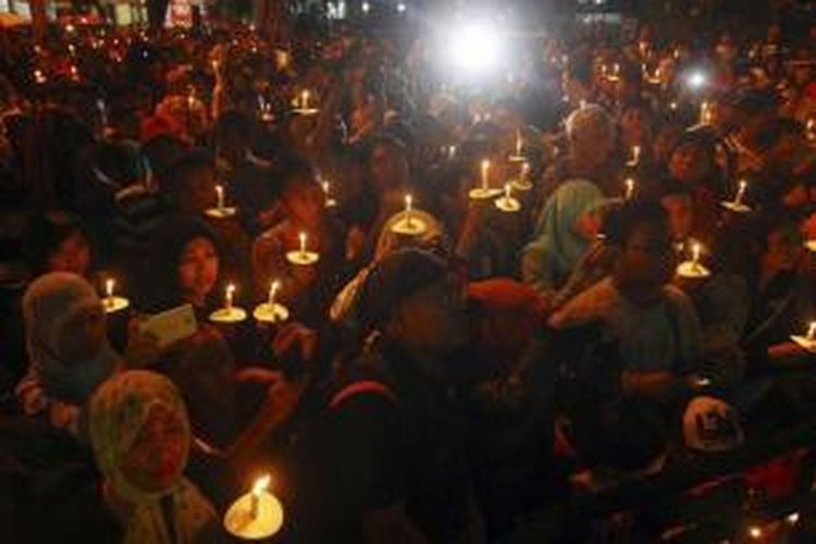 Warga menyalakan lilin dalam acara doa bersama bagi korban jatuhnya pesawat AirAsia QZ8501 di Surabaya, Jawa Timur, 31 Desember 2014.