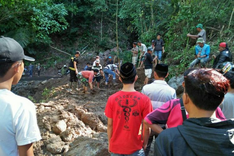 Aparat kepolisian dibantu ratusan warga berupaya mebersihkan material longsor yang menerjang jalur Trans Sulawesi, Kecamatan Tombolopao, Kabupaten Gowa, Sulawesi Selatan. Jumat, (23/6/2017).