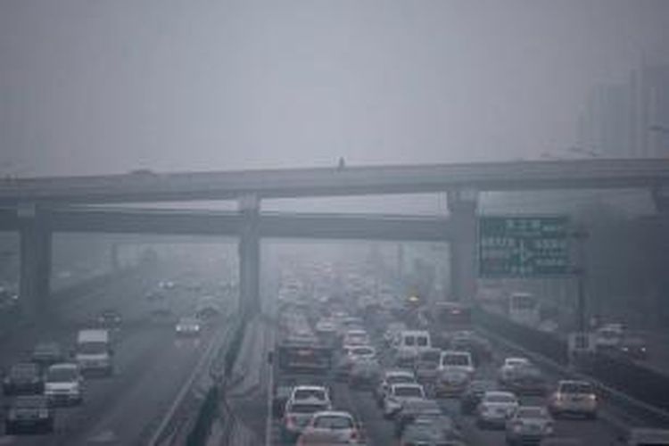 Seorang pria (tengah atas) berjalan di sepanjang jembatan penyeberangan saat kabut asap melanda Beijing, Selasa, 8 Desember 2015. Pemerintah Kota Beijing, Senin sore, untuk pertama kalinya dalam sejarah menaikan status kabut menjadi darurat berstatus ?berwarna merah? yang merupakan status darurat paling tinggi.