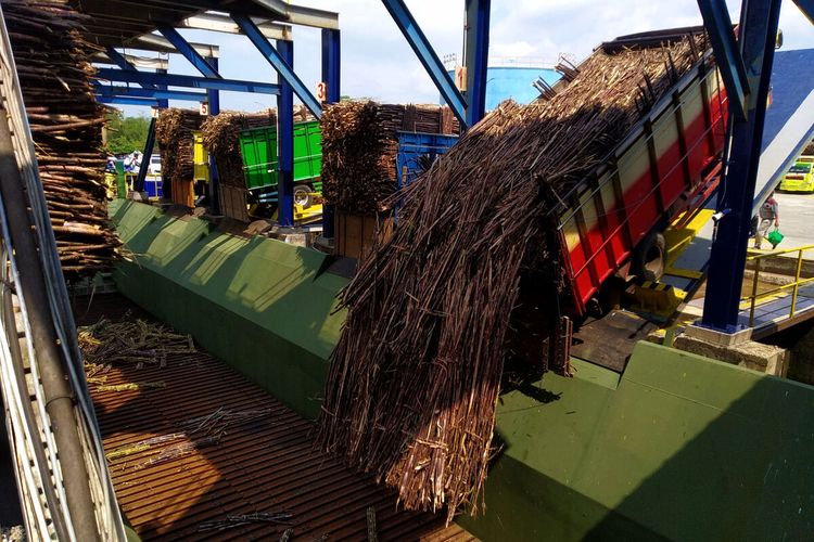 Truk-truk pemasok tebu menumpahkan muatan ke conveyor di lokasi pembokaran muatan di area pabrik gula PT Rejoso Manis Indo di Desa Rejoso, Kecamatan Binangun, Kabupaten Blitar, Rabu (25/5/2022)