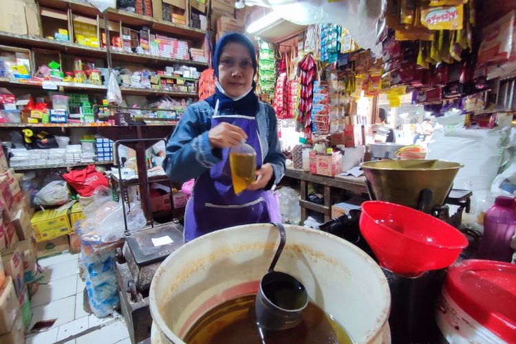 Yuli salah satu pelayan di Toko Sembako Handoko Pasar Pagi Kota Cirebon, Jawa Barat, menunjukan minyak goreng curah yang baru saja dia bungkus, Senin (27/6/2022).