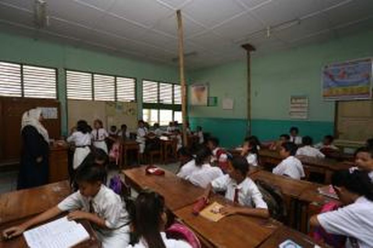 Siswa SDN 07 Pademangan Barat, Jakarta Utara, tengah belajar di ruang kelas yang atapnya disangga oleh bambu, Senin (2/12/2013). Guru dan siswa sekolah tersebut khawatir atap kelas itu rubuh.