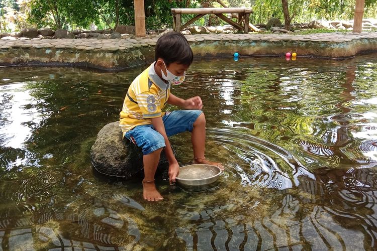 Seorang pengunjung anak bermain di kolam ikan di Puri Mataram, Sleman, DIY.