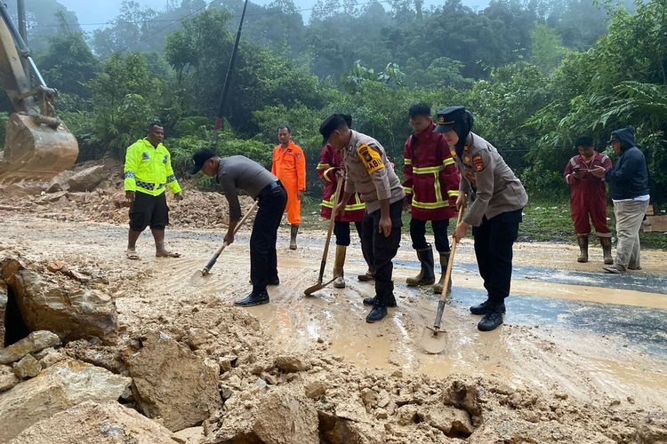 Petugas kepolisian dan BPBD berupaya menyingkirkan bebatuan longsor yang menutup badan jalan lintas Riau-Sumbar, di Desa Merangin, Kecamatan Kuok, Kabupaten Kampar, Riau, Selasa (21/3/2023).