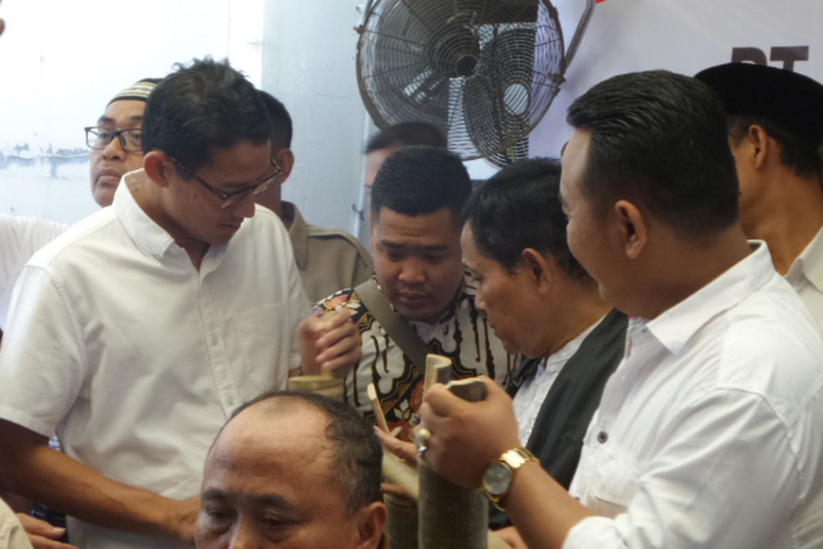 Calon wakil gubernur DKI Jakarta Sandiaga Uno memegang kentongan sebagai simbol partisipasi pengurus RT dan RW dalam memenangkan dia bersama pasangannya, Anies Baswedan, di Ciracas, Jakarta Timur, Minggu (26/3/2017).