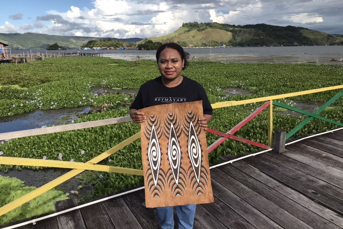 Serra Esterlin Ohee (24), pengusaha muda asal Pulai Asei Besar menunjukkan hasil kerajinan kulit kayu dari pohon Khombouw di Dermaga Pantai Khalkote, Jayapura, Papua pada Jumat (22/7/2022) siang. Serra yang juga merupakan Pegawai Negeri Sipil berstatus honerer membuat merek usahanya yakni Reymay Art.