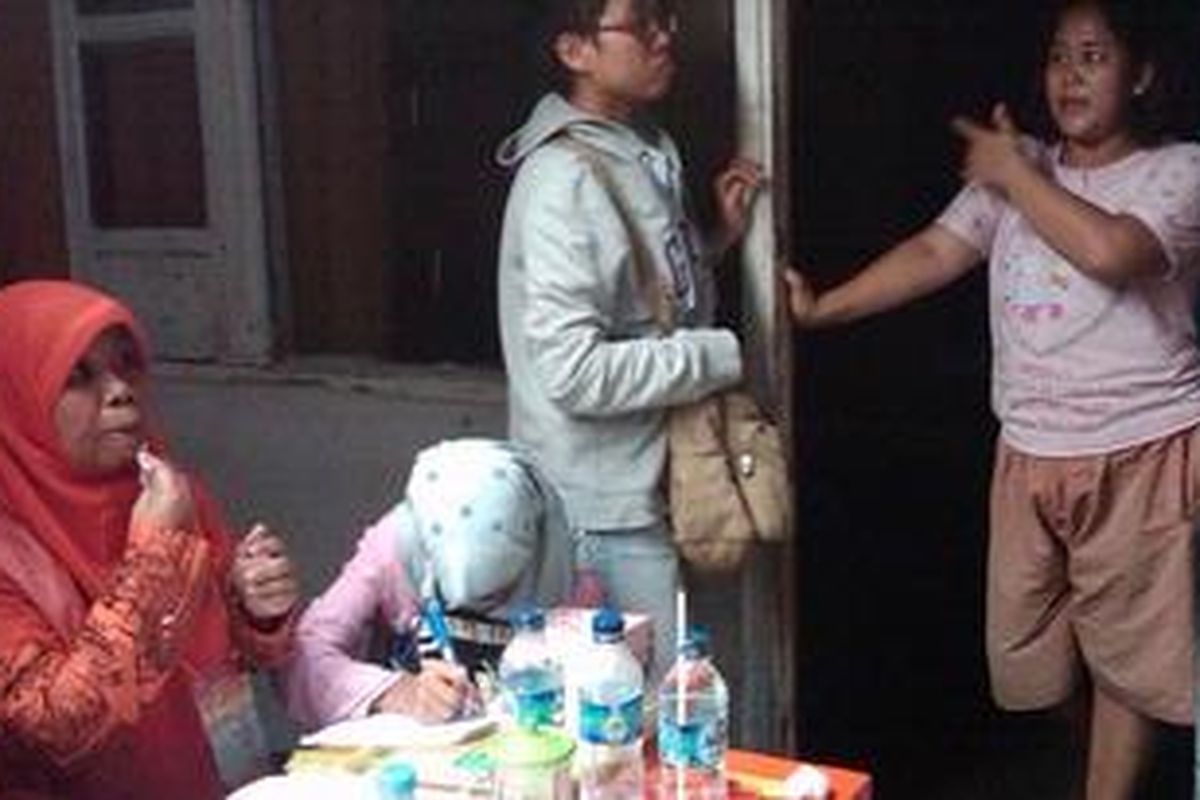 Aini Yulianti (23) (berdiri di pintu), warga RT 06 RW 05 Menteng Atas, Jakarta Selatan, tidak mendapatkan hak pilihnya dalam Pilkada DKI Jakarta 2012 padahal dirinya mengaku selalu terdaftar dalam setiap pemilihan. Ironisnya, Yuli hanya bisa memandangi kesibukan pemilihan yang berlanhsung dari pagi di halaman rumahnya sendiri, Rabu (11/7/2012). 