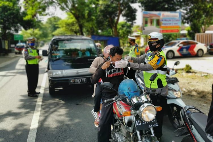 Petugas dari Satlantas Polres Karanganyar memakaikan masker kepada pengendara sepeda motor.