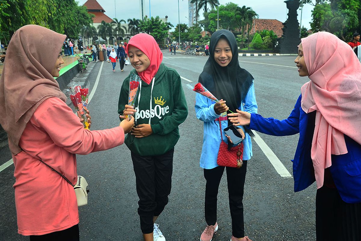 Peserta aksi membagikan bunga kepada seorang perempuan saat memperingati Hari Perempuan Sedunia di Kudus, Jawa Tengah, Minggu (8/3/2020). Aksi oleh Mahasiswa Pergerakan Mahasiswa Muslim Indonesia (PMII) dengan membagikan bunga itu sebagai bentuk seruan agar lebih menghargai hak perempuan dan menghentikan segala bentuk kekerasan dan diskriminasi terhadap perempuan.