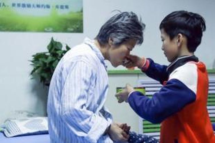 Shangguan (10) menyuapi neneknya, Shen yang sedang dirawat di sebuah rumah sakit di Jinan, China untuk memulihkan tubuhnya yang lumpuh akibat stroke. 