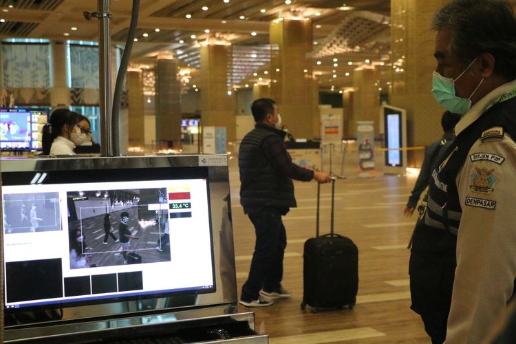 Petugas tengah memantau suhu tubuh para penumpang pesawat yang tiba di Bandara Internasional I Gusti Ngurah Rai, Bali. 