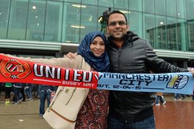 Suporter membentangkan spanduk bergambar logo Manchester United dan Manchester City, di depan Stadion Old Trafford, sebelum laga Premier League, antara kedua kubu, Minggu (12/4/2015).