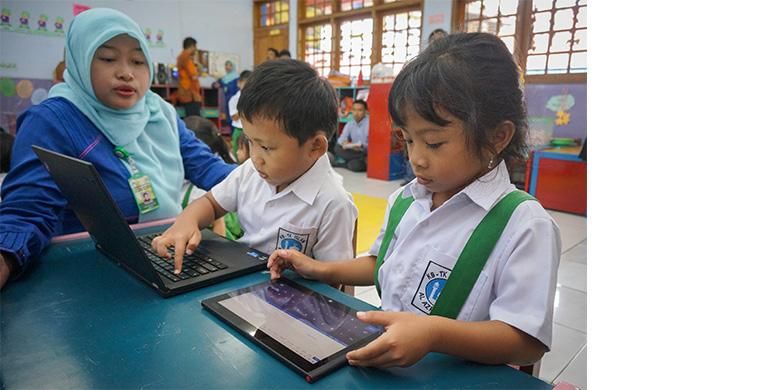 Nura Uma Annisa, guru komputer TK Islam Al-Azhar 22 Semarang, mendampingi anak muridnya dalam menggunakan tablet dan laptop untuk belajar, Selasa (17/12/2013)