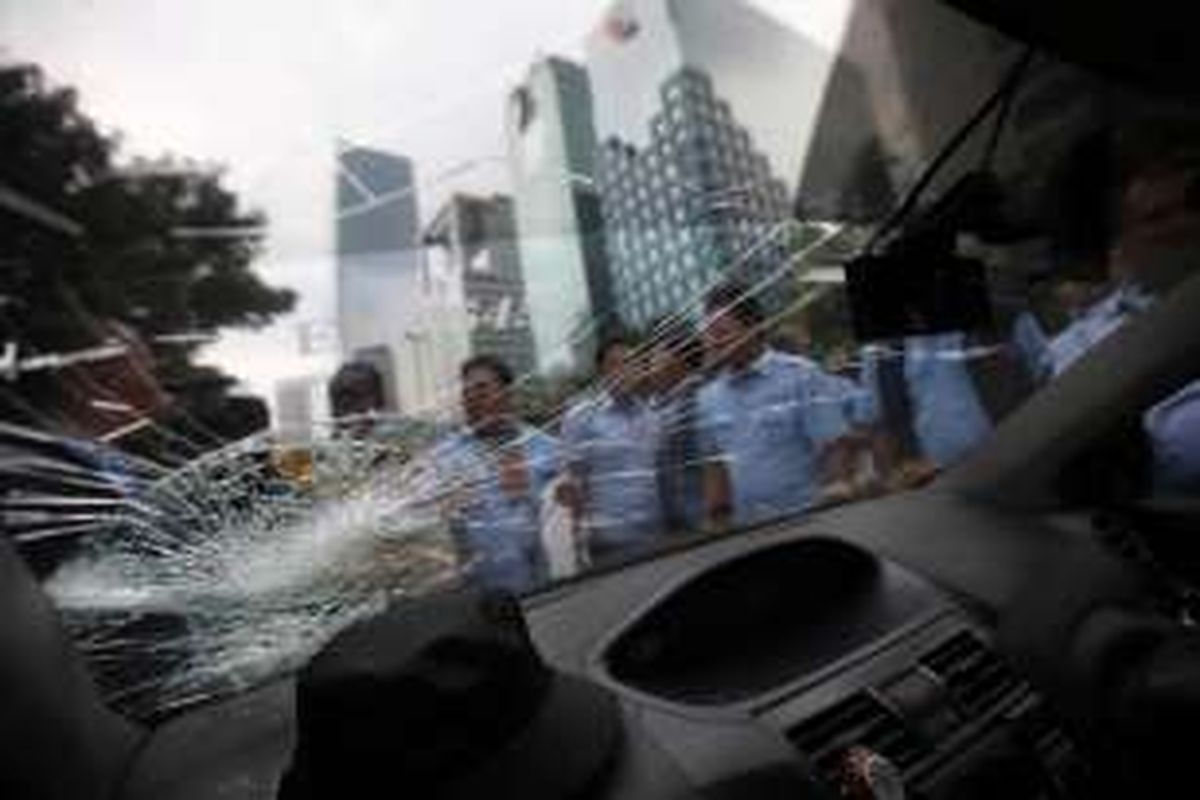 Sopir taksi melihat kaca taksi rekannya yang retak setelah dilempari oleh warga saat melintas di Jalan Jenderal Sudirman, Karet, Jakarta, Selasa (22/3/2016). Sopir taksi berunjuk rasa menolak beroperasinya angkutan berbasis aplikasi online.