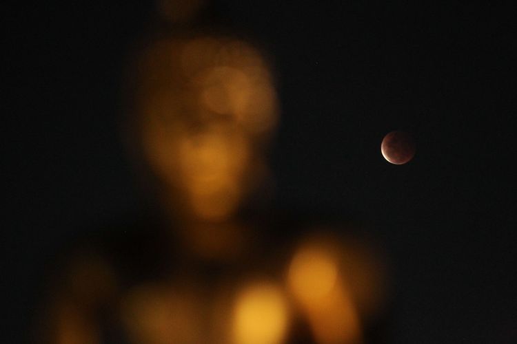 Gerhana bulan total dengan latar depan patung Budha di Vihara Hemadhiro Mettavati, Cengkareng, Jakarta Barat, Rabu (26/5/2021). Gerhana Bulan Total tanggal 26 Mei 2021 ini dikenal juga dengan Super Blood Moon (Bulan Merah Super), karena terjadi saat bulan di di jarak terdekat dengan Bumi (Perigee).