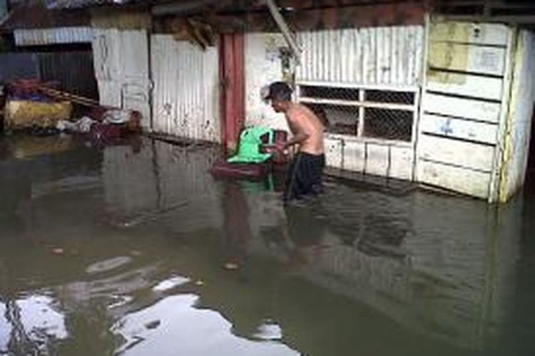 Seorang pria paruh baya di Kabupaten Bone, Sulawesi Selatan berupaya mengevakuasi barang rumah tangganya akibat terendam banjir. Minggu,(17/11/2013).