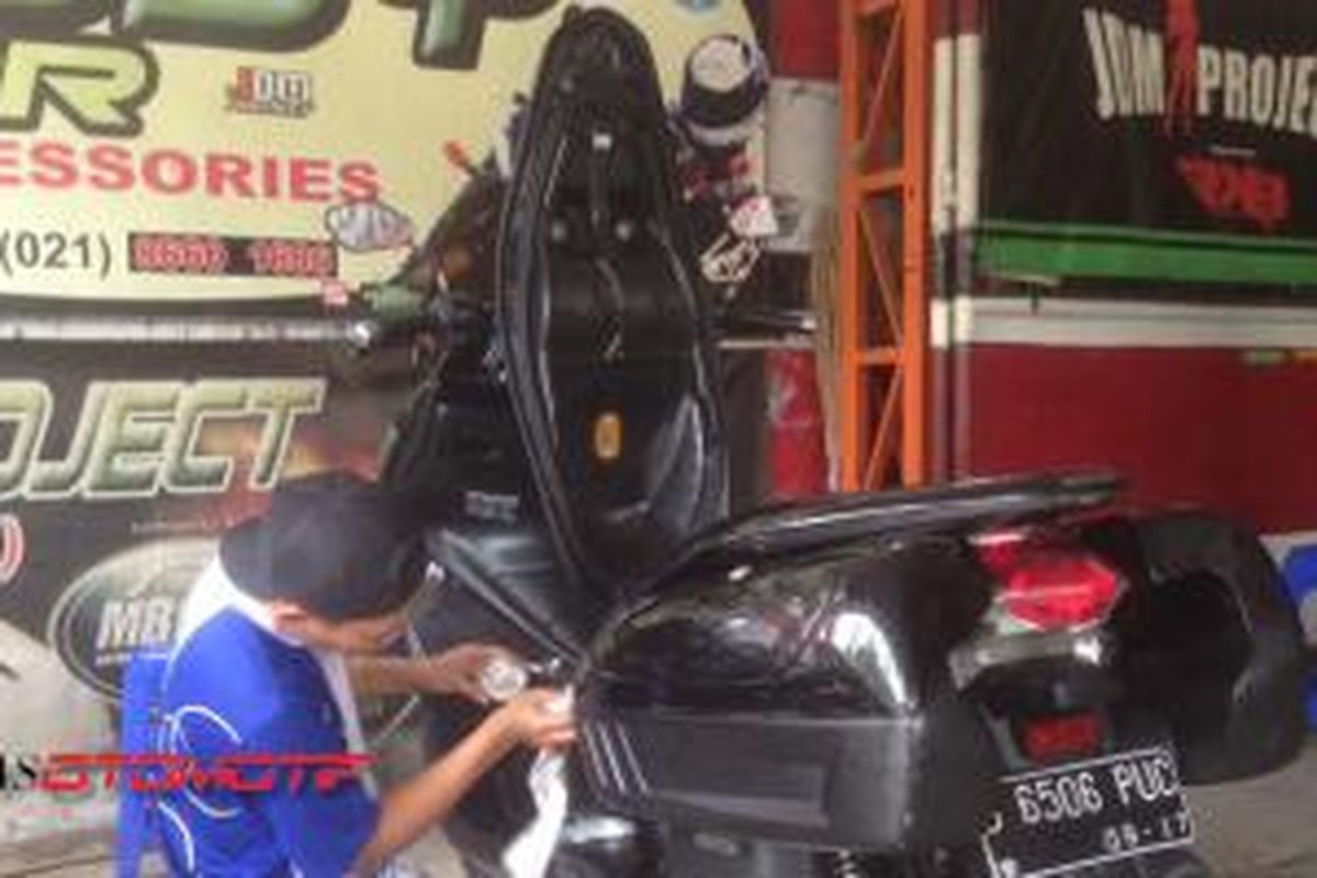 Salah seorang pegawai JDM Project sedang melakukan poles bodi di sepeda motor Honda PCX.