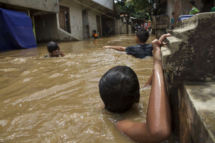 Sejumlah warga melintasi genangan banjir yang merendam wilayah Pejaten Timur, Pasar Minggu, Jakarta Selatan, Sabtu (8/2/2020). Luapan air kali ciliwung tersebut merendam pemukiman padat penduduk hingga ketinggian 2 meter.
