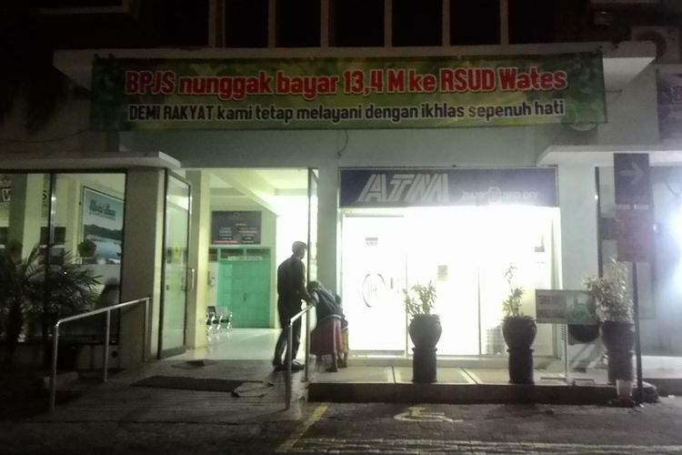 RSUD Wates kesal pada BPJS Kesehatan hingga memasang sebuah spanduk di atas pintu masuk gedung sayap barat, Minggu (29/7/2018) petang. Spanduk itu bertuliskan BPJS nunggak bayar 13,4 M ke RSUD Wates; DEMI RAKYAT kami tetap melayani dengan ikhlas sepenuh hati. 