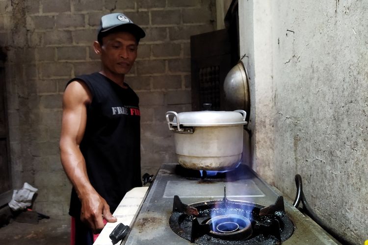 Teguh Pratikno menghidupkan kompor biogas di rumahnya di Dusun Dungus, Desa Mundu, Kecamatan Tulung, Kabupaten Klaten, Selasa (12/10/2021). Berdasarkan Biogas User Survey 2020, penghematan energi untuk memasak bisa mencapai Rp 50.000.