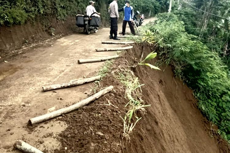 Warga menandai bagian jalan yang longsor dengan kayu di Dusun Tlogosari, Desa Sumberurip, Kecamatan Doko, Kabupaten Blitar, Sabtu (30/10/2021)