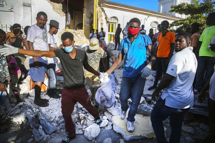 Orang-orang membawa mayat yang ditemukan dari puing-puing gempa bumi yang menghancurkan rumah di Les Cayes, Haiti, Minggu, 15 Agustus 2021.