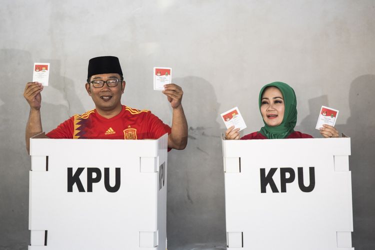 Calon Gubernur Jawa Barat nomor urut satu Ridwan Kamil (kiri) bersama istri Atalia Praratya (kanan) menunjukkan surat suara saat menggunakan hak pilih di TPS 21 Bandung, Jawa Barat, Rabu (27/6/2018). Pilgub Jabar diikuti empat pasang cagub dan cawagub dengan jumlah daftar pemilih tetap (DPT) sebanyak 31.735.133 pemilih. 

