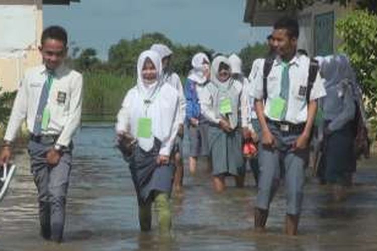 siswa smkn 1 pemulutan melintasi banjir saat pulang ujian akhir nasional di sekolahnya...
