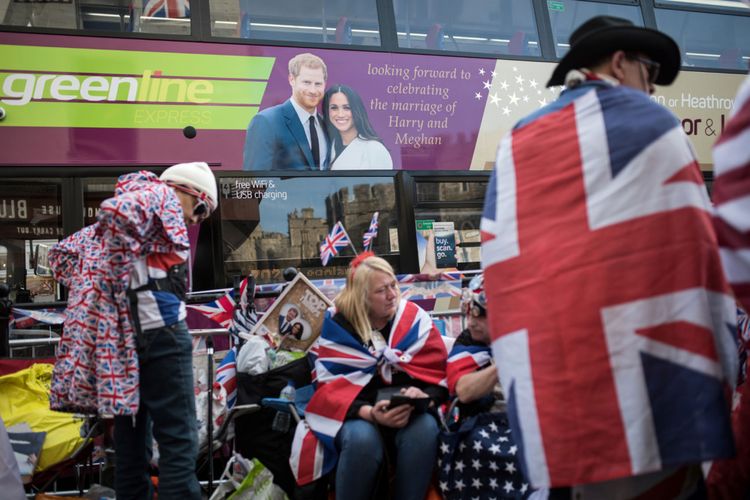 Sebuah bus bergambar Pangeran Harry adan Meghan Markle melewati orang-orang yang menunggu di jalur yang akan dilalui pengantin itu di Windsor 17 Mei 2018, dua hari sebelum Royal wedding dilaksanakan. Harry dan Meghan Markle akan menikah 19 Mei di St Georges Chapel di Windsor Castle.  AFP PHOTO / OLI SCARFF