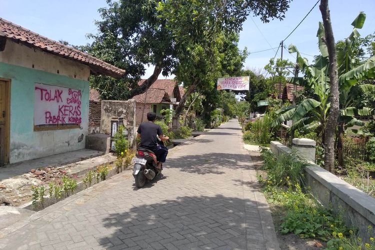 Spanduk protes warga atas bau busuk dari pabrik pupuk organik bertebaran di sepanjang jalan Dusun Templek, Desa Tanjungkalang, Kecamatan Ngronggot, Nganjuk, Senin (11/10/2021).