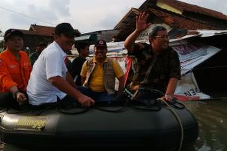 Gubernur Jawa Barat Ahmad Heryawan saat berlayar menaiki perahu bersama aparat TNI memantau banjir di Kabupaten Bandung, Minggu, (21/12/2014). Saaat itu, posisi Aher sedang menyusul perahu Menteri PAN - RB Yuddy Chrisnandy yang telah berjalan berlayar lebih dulu.