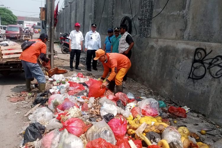 Petugas kebersihan saat membersihkan sampah yang memenuhi trotoar jalan di Jalan Bosih Raya, samping pasar Cibitung, Kabupaten Bekasi.