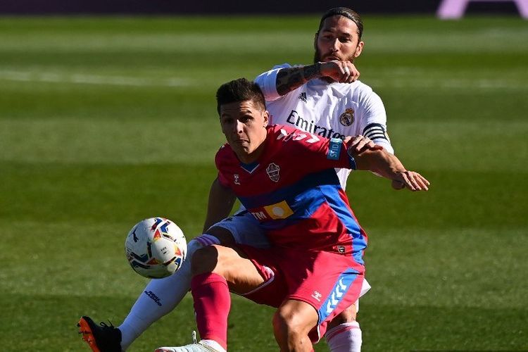 Bek Spanyol Real Madrid Sergio Ramos (belakang) menantang penyerang Argentina Elche Guido Carrillo selama pertandingan sepak bola Liga Spanyol antara Real Madrid dan Elche di stadion Alfredo Di Stefano di Valdebebas, timur laut Madrid, pada 13 Maret 2021.