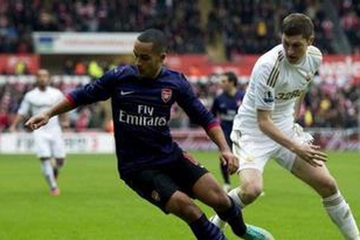 Penyerang Arsenal, Theo Walcott (kiri), mencoba melewati hadangan bek Swansea City, Ben Davies (kanan), pada laga di Stadion Liberty, Minggu (6/1/2013).