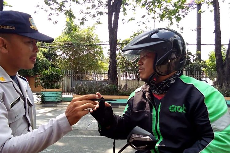 Petugas Dishub memberhentikan pengemudi ojek online karena lintasi jalur sepeda di Jalan Tomang Raya 