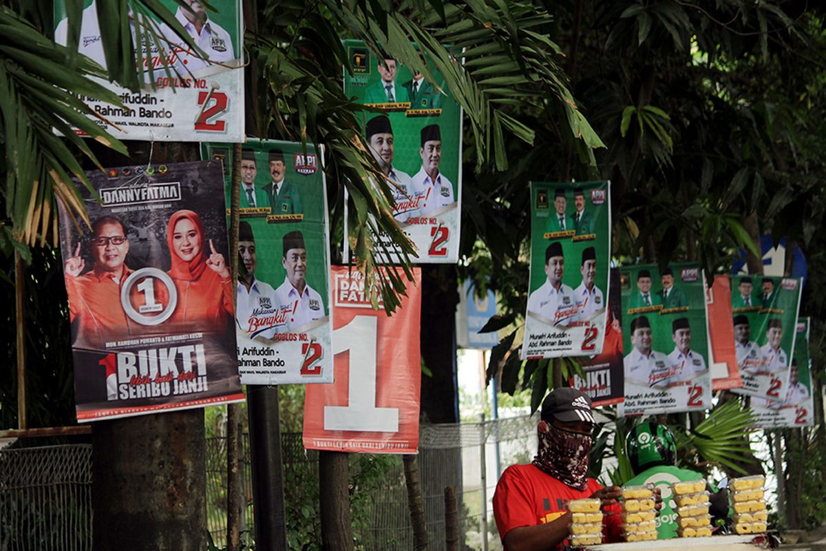 Pedagang kaki lima menjajakkan dagangannya di dekat alat peraga kampanye (APK) yang terpasang di pohon dan tiang listrik di Makassar, Sulawesi Selatan, Rabu (14/10/2020). Pemasangan sejumlah APK tersebut melanggar aturan Komisi Pemilihan Umum (KPU) Kota Makassar melalui surat keputusan (SK) nomor 340/PL.02.4-kpt/7371/KPU-kot/IX/2020 tentang pemasangan APK pada Pilkada 2020.