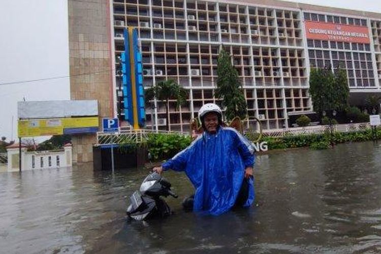 Pekerja kebersihan di Stasiun Tawang, Prasongko saat menerabas banjir untuk berangkat kerja, Kota Semarang, Sabtu (31/12/2022)