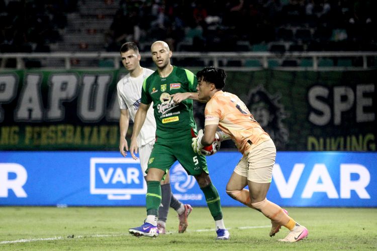 Pemain belakang Persebaya Surabaya Risto Mitrevski menjaga penjaga gawang Ernando usai menangkap bola tendangan pemain PSM Makassar saat laga pekan ke-23 Super League 2025-2026 di Stadion Gelora Bung Tomo Surabaya, Rabu (25/2/2026) malam.