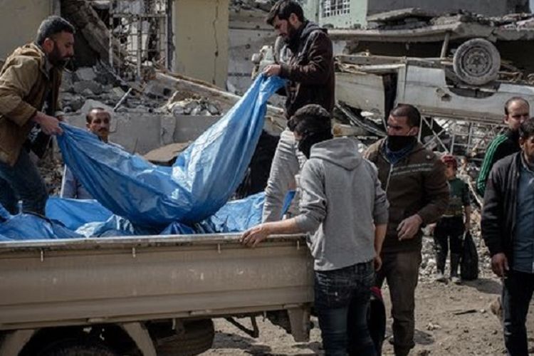 Beberapa pria dari tim penyelamat mengangkat mayat-mayat korban serangan udara di sebuah rumah di Mosul barat, Irak.