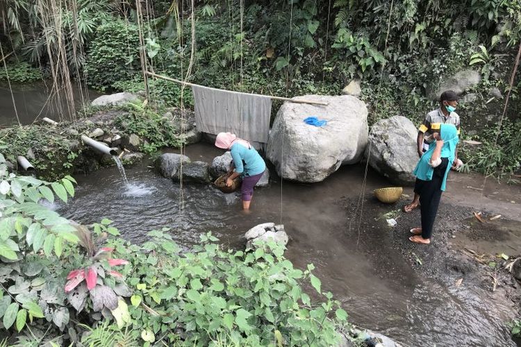 Warga mencuci salak yang tertutup abu di aliran sungai di Dusun Kebondeli Utara, Kecamatan Candipuro, Kabupaten Lumajang, Selasa (7/12/2021). (ANTARA/Fiqih Arfani)
