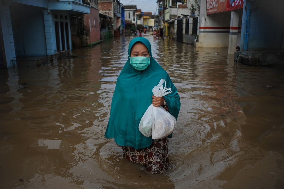 Warga melintasi  banjir yang melanda Bojongasih, Dayeuhkolot, Kabupaten Bandung, Jawa Barat, Jumat (25/12/2020). Hujan lebat yang melanda Bandung Raya sejak Kamis (24/12) sore hingga malam hari menyebabkan 7.364 rumah di Dayeuhkolot dan Baleendah terendam banjir akibat luapan Sungai Citarum dengan ketinggan 30 hingga 150 sentimeter. ANTARA FOTO/Raisan Al Farisi/nz